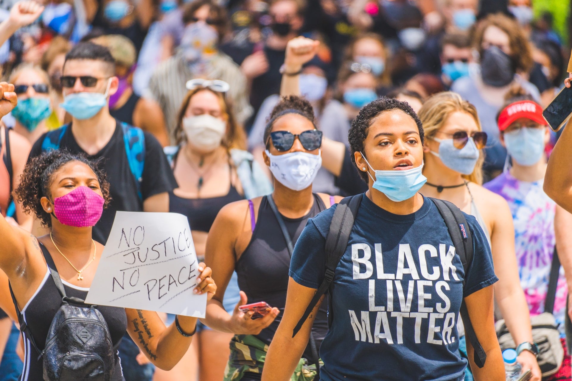 A young woman wearing a mask and black lives matter t-shirt 
                              marching in a #BlackLivesMatter public demonstration in Cincinnati.